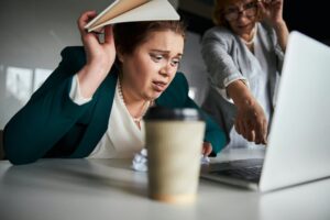 Ashamed employee hiding under folder while looking at her mistake