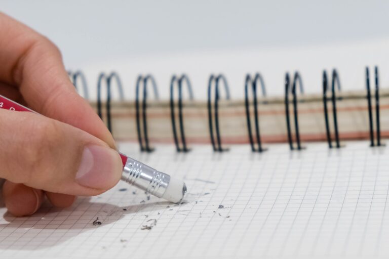 pencil eraser removing a written mistake on a note book, school and mistake concept.
