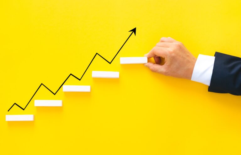 Businessman hand arranging wood block stacking as step stair with growth arrow. Business growth suc